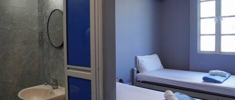 A hotel room with a bathroom, a bed with a blue towel, and a window with daylight.