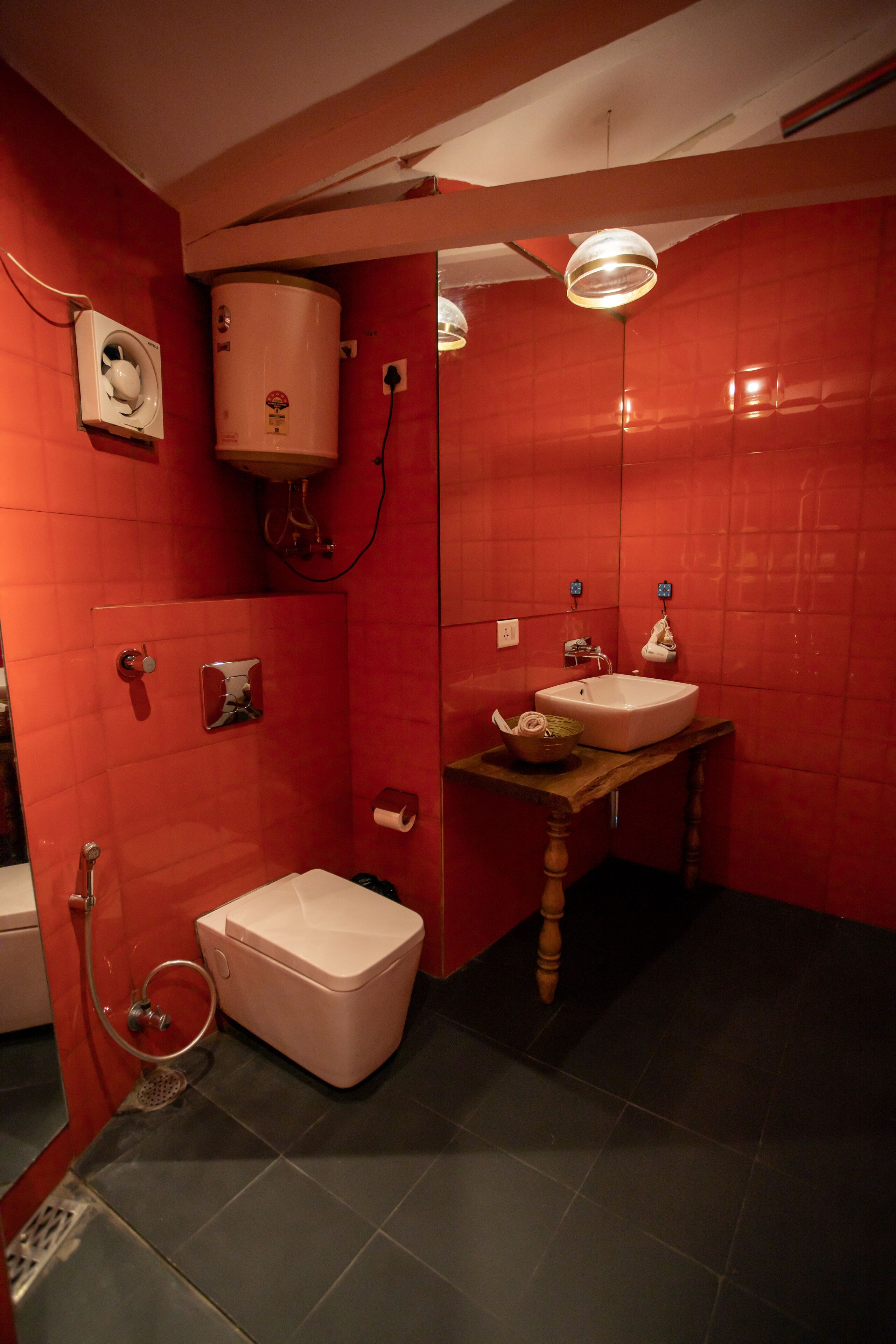 Casa de banho com paredes vermelhas, lavatório branco e sanita.