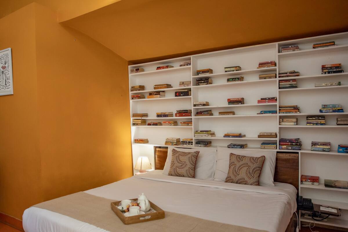 Une chambre avec un grand lit, une bibliothèque et une lucarne.