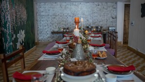 Une longue table à manger, décorée de bougies, d’assiettes et d’un gâteau, dans une pièce dont le mur est en briques et le sol en bois.