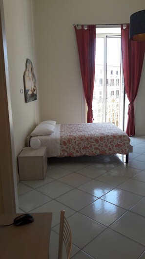 A bedroom with a bed, a chair, a desk, and a window with curtains. - La Casa di Elvira (Naples)