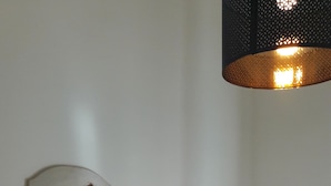 Ein Schlafzimmer mit einem Bett, Kissen, einem Nachttisch und einer Wandlampe.