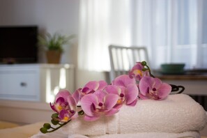 Una toalla blanca con un grupo de orquídeas rosadas sobre ella.