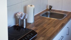 Una cocina moderna con armarios blancos, encimera de madera, pileta de acero inoxidable y placa de inducción integrada.