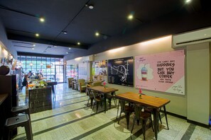 Ein modernes Café mit Tischen, Stühlen, großen Fenstern und Postern an den Wänden.
