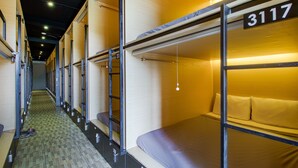 Een rij stapelbedden in een slaapzaal, met een nummerbordje boven elk bed.