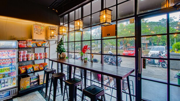 Een restaurant met een bar, zitplaatsen en uitzicht op de straat door grote ramen.