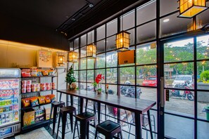 A restaurant with a bar area, seating, and a view of the street through large windows. - My Studio Hotel Juanda Airport Surabaya - Hostel (Sidoarjo)