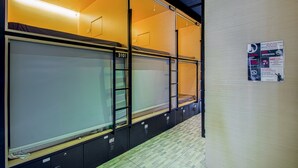 Een slaapzaal met stapelbedden, genummerde deuren en een bordje met een rookverbod.