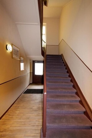 Un corridoio con una scala in legno che conduce a un piano superiore.