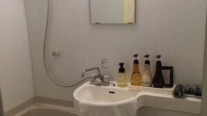 Une petite salle de bain avec une baignoire, un lavabo et des toilettes. On trouve des articles de toilette sur le comptoir du lavabo.