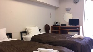 Une chambre d’hôtel avec deux lits, une télévision, un bureau et un miroir.