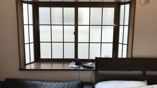 A room with a large window, a bed, and a desk with a laptop and papers. - Tokyo Urban Flat Hotel 201 (Tokyo)