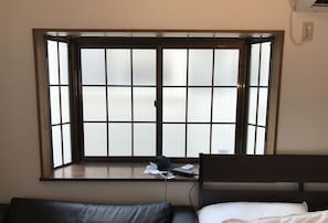 A room with a large window, a bed, and a desk with a laptop and papers. - Tokyo Urban Flat Hotel 201 (Tokyo)