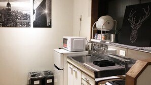 A modern kitchen with white cabinets, a stainless steel sink, and a microwave. There are two trash bins labeled "Flammable Trash" and "Cans." - Tokyo Urban Flat Hotel 201 (Tokyo)