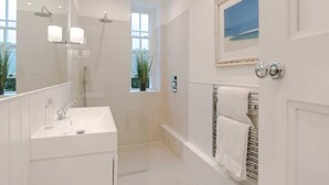 A modern bathroom with a large mirror, a sink, a shower, and a towel rack. - Bright and Leafy 1 Bedroom Flat in the Heart of Chelsea (London)
