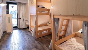 A room with bunk beds, wooden flooring, a small kitchenette, and a view through a door. - Trip & Sleep Hostel (Nagoya)