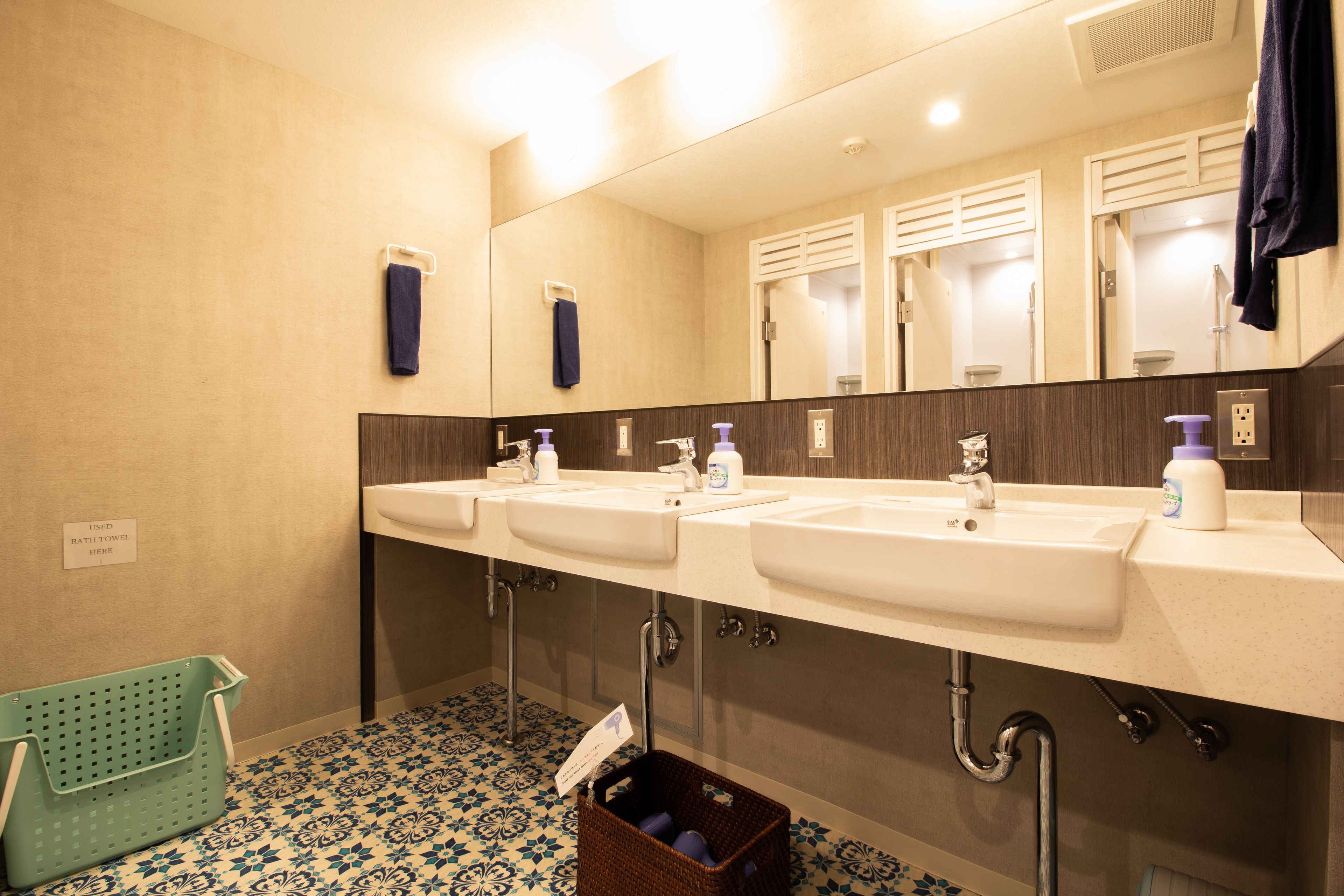 Un baño con dos lavamanos, un espejo y un cubo de basura.