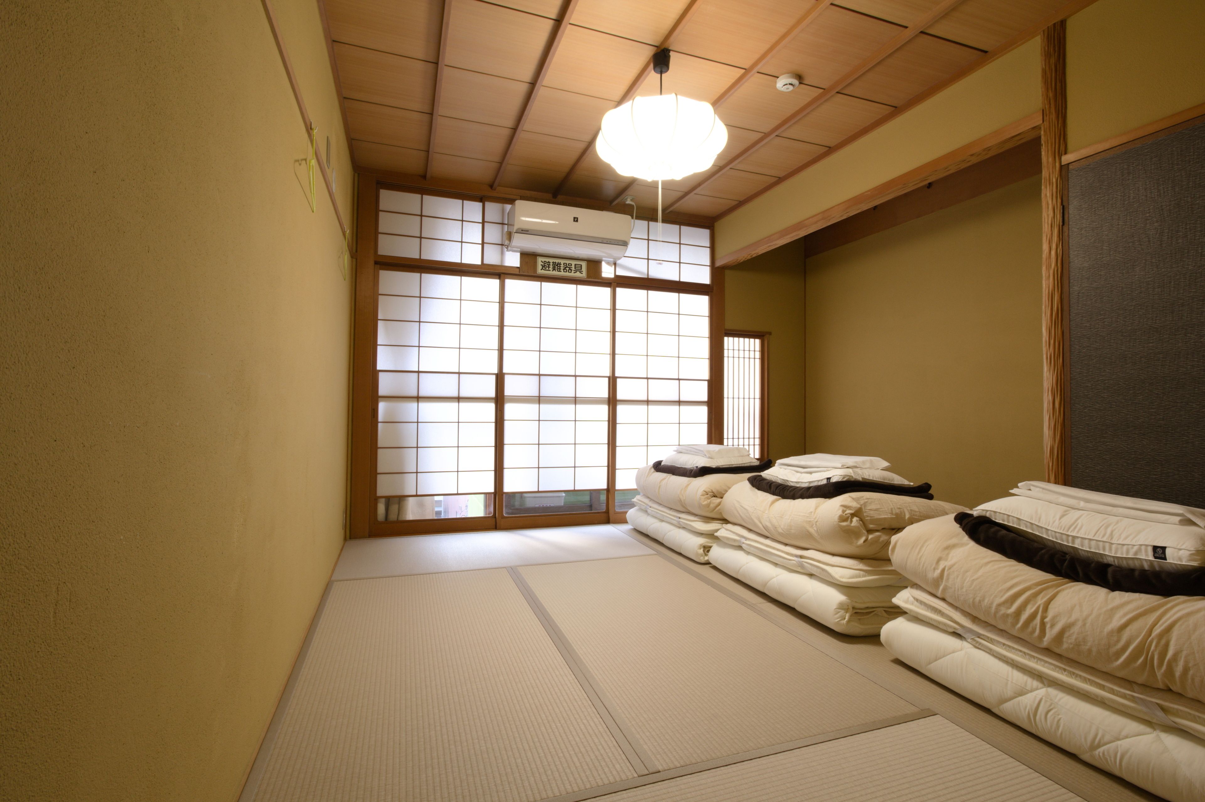 Una habitación japonesa tradicional con suelo de tatami, futón, puertas correderas shoji y ventilador de techo.