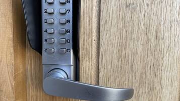 Un teclado de acceso sin contacto en una puerta de madera.