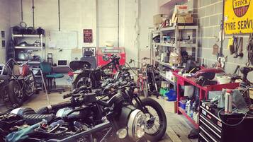 Un atelier de réparation de motos où l’on trouve différents modèles de motos, ainsi que divers outils et équipements.