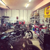 Un taller de reparación de motocicletas con varias motos, herramientas y equipo.