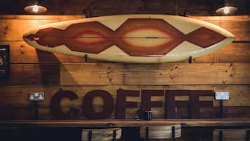 Una tabla de surf con un diseño único colgada en una pared de madera sobre un mostrador donde se lee la palabra "COFFEE".