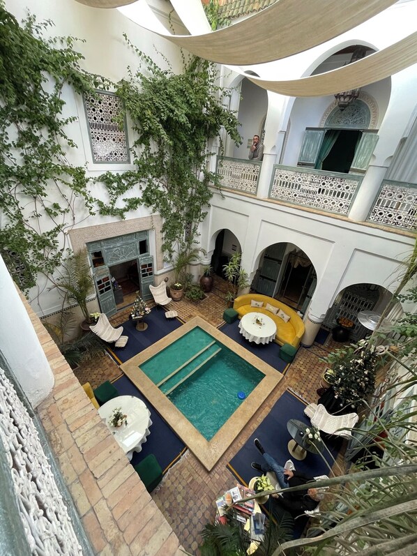 Un patio con piscina, zonas de estar y chimenea.