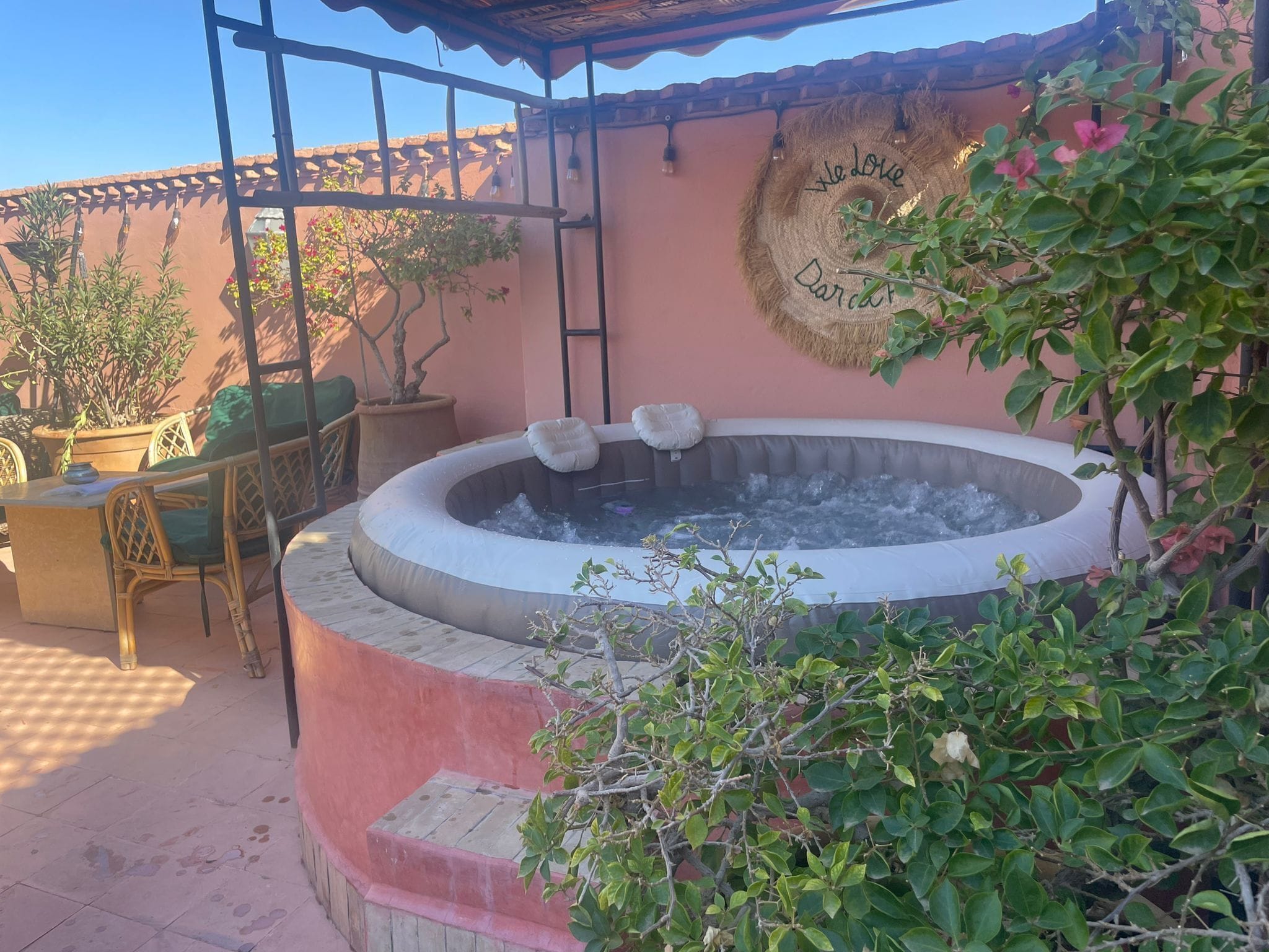 Un bain à remous entouré de plantes en pot et de meubles d’extérieur.