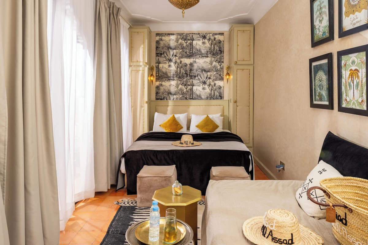 A hotel room with a bed, a small table with a tray, a hat, and a woven basket.