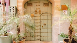 Une porte marocaine traditionnelle, ornée de motifs métalliques complexes, et flanquée de plantes en pot.