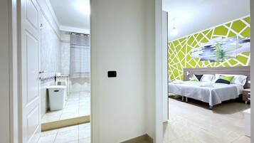 A hotel room with a bed, a nightstand, a wall-mounted artwork, and a bathroom visible through an open door.