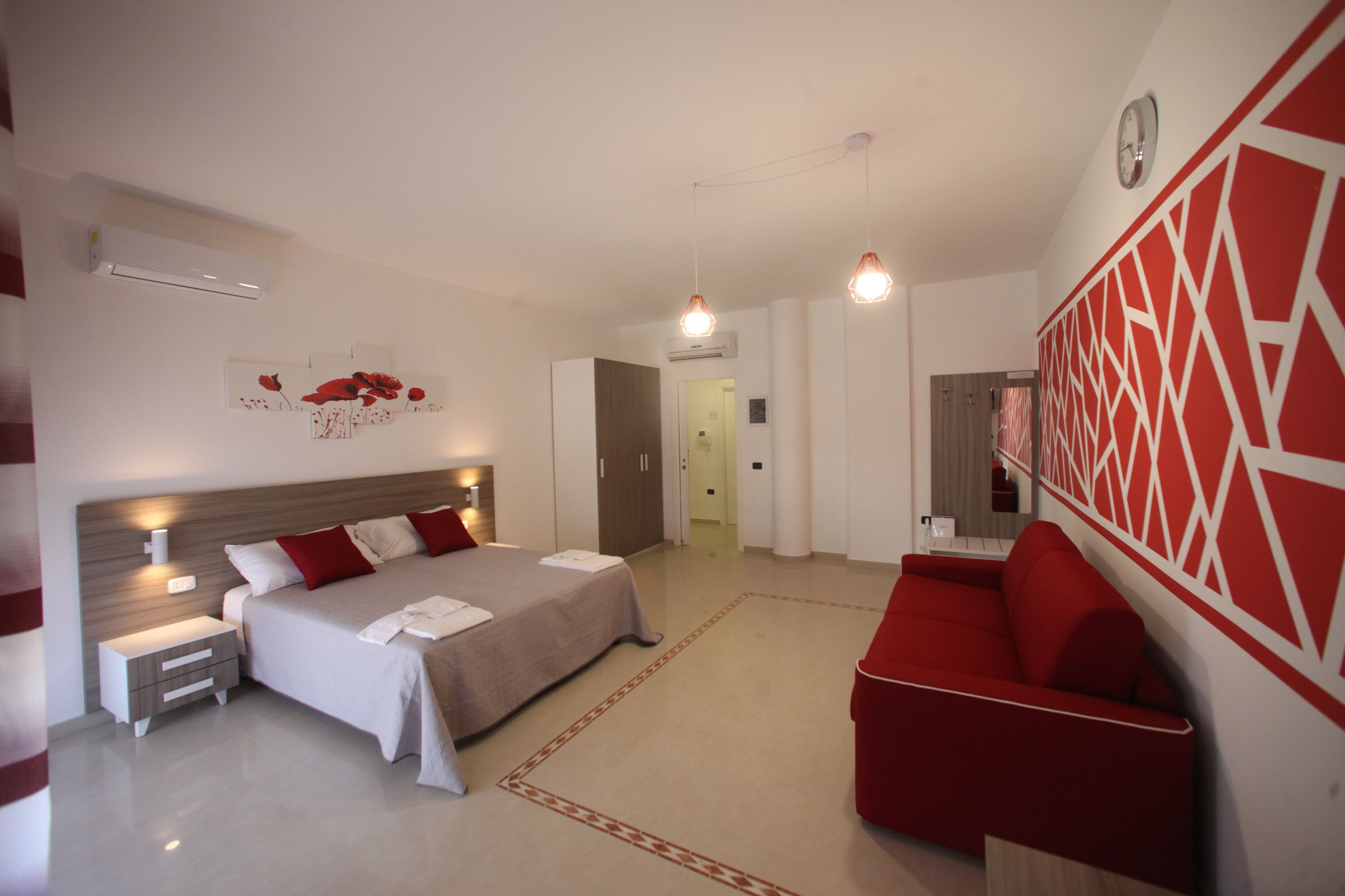 Une chambre à coucher moderne avec un lit, des tables de chevet, un canapé rouge et un élément décoratif mural.