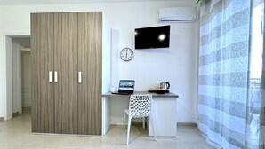 A modern room with a wooden wardrobe, a desk with a laptop, a kettle, and a TV on the wall. - Bed & Breakfast Corso Roma (Apricena)