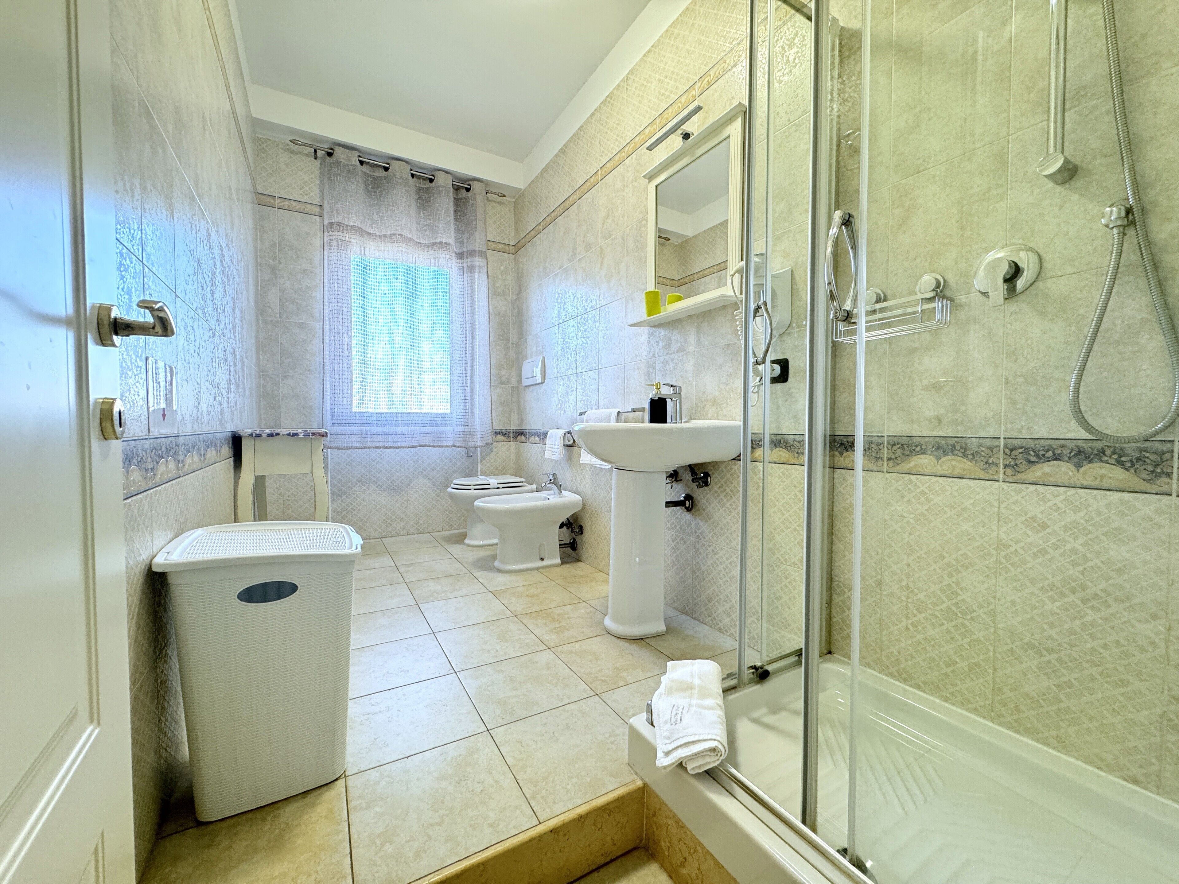 A bathroom with a glass-enclosed shower, a toilet, a bidet, and a sink.