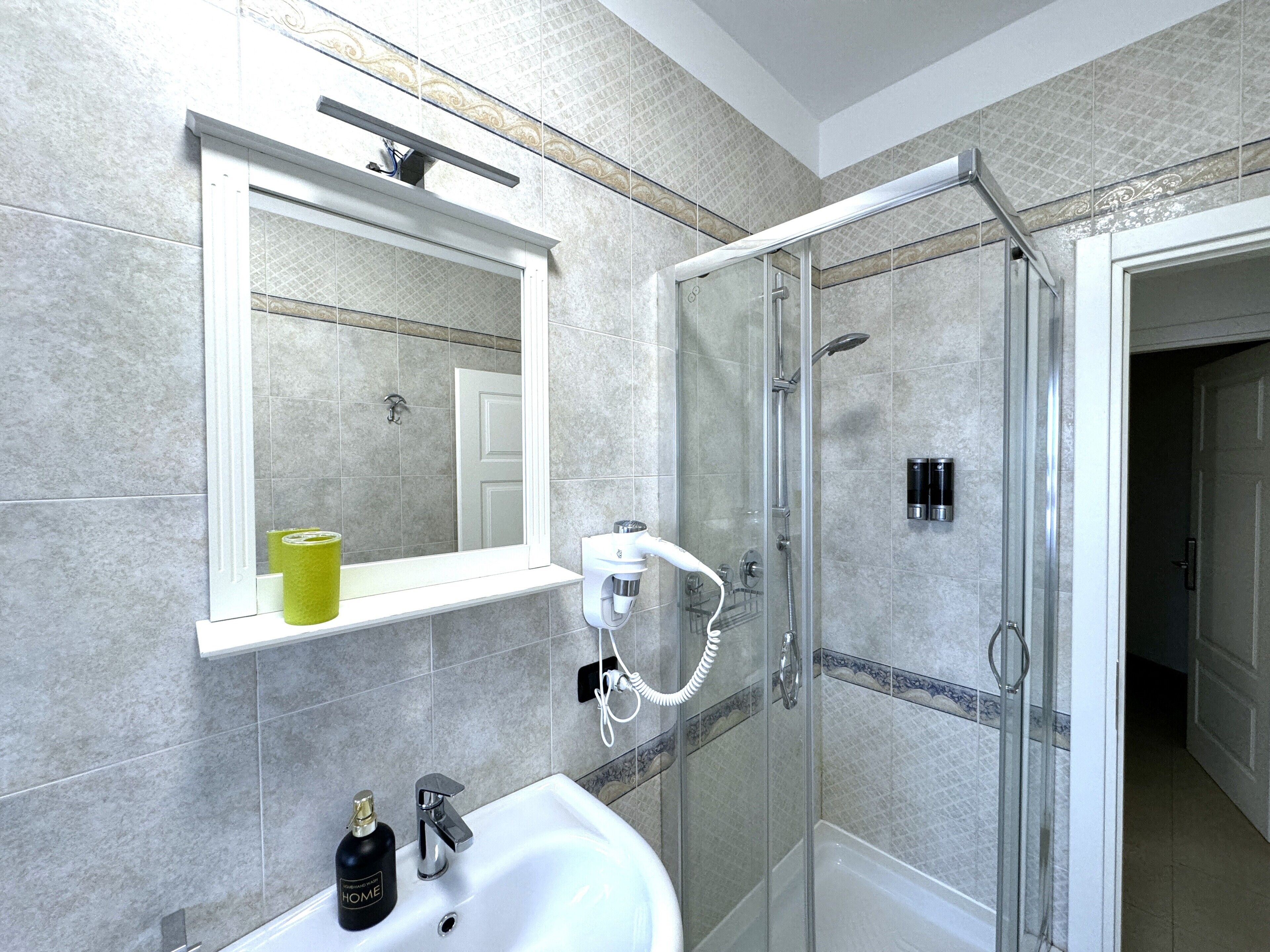 A modern bathroom with a glass-enclosed shower, a white sink, and a mirror above it.