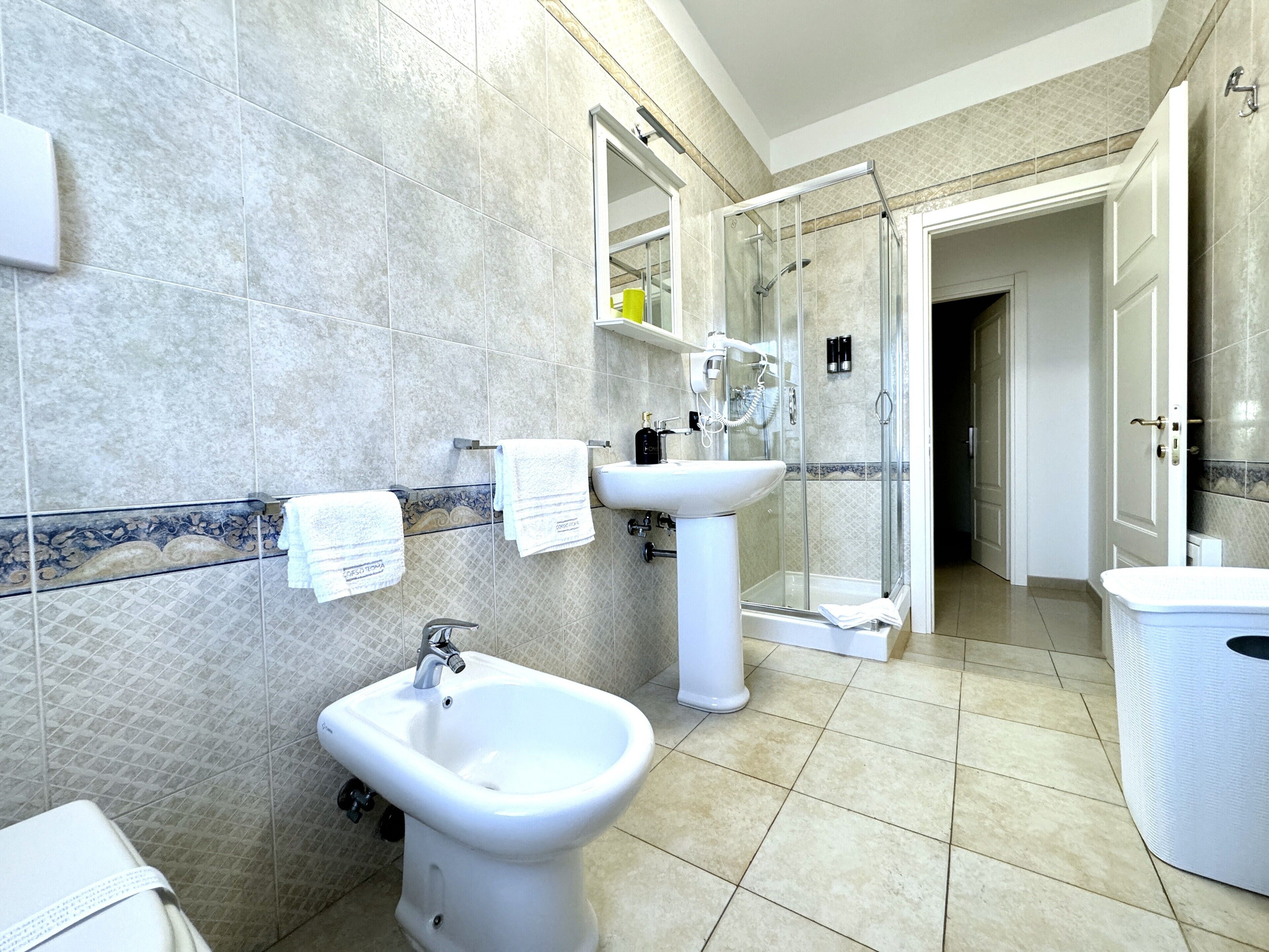 Ein modernes Badezimmer mit integriertem Bidet, Waschbecken und Duschkabine aus Glas.