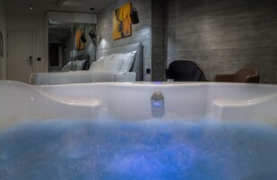 A modern bathroom with a large bathtub, a mirror, and a white sofa.