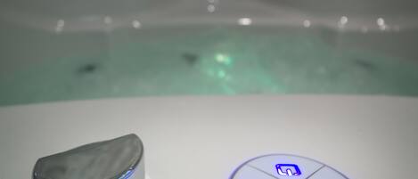 A bathtub with a marble-like texture and a control panel with illuminated buttons.