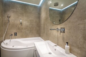 A modern bathroom with a bathtub, a sink, and a shower.