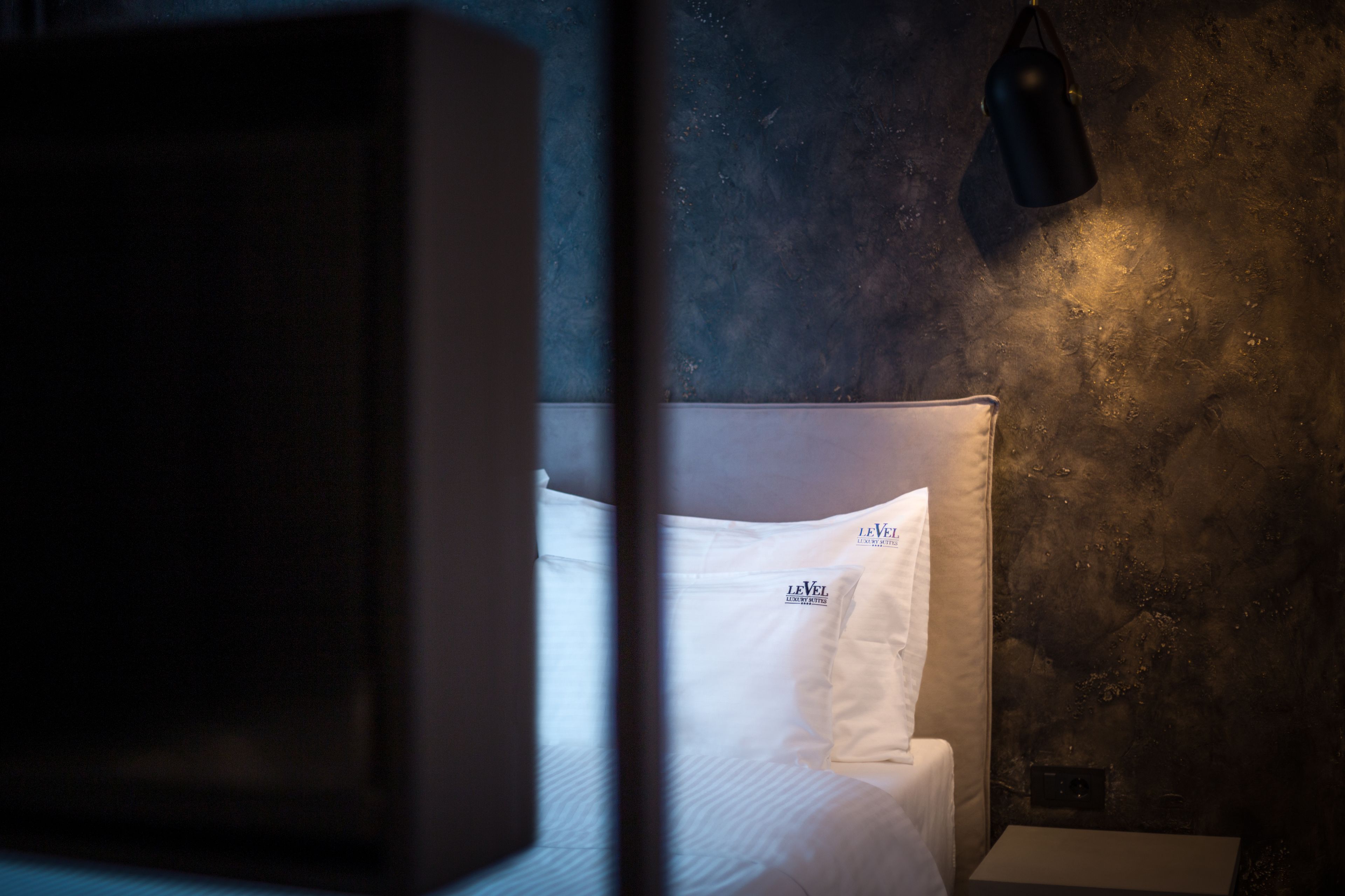 A hotel room with a bed, a nightstand, and a lamp.