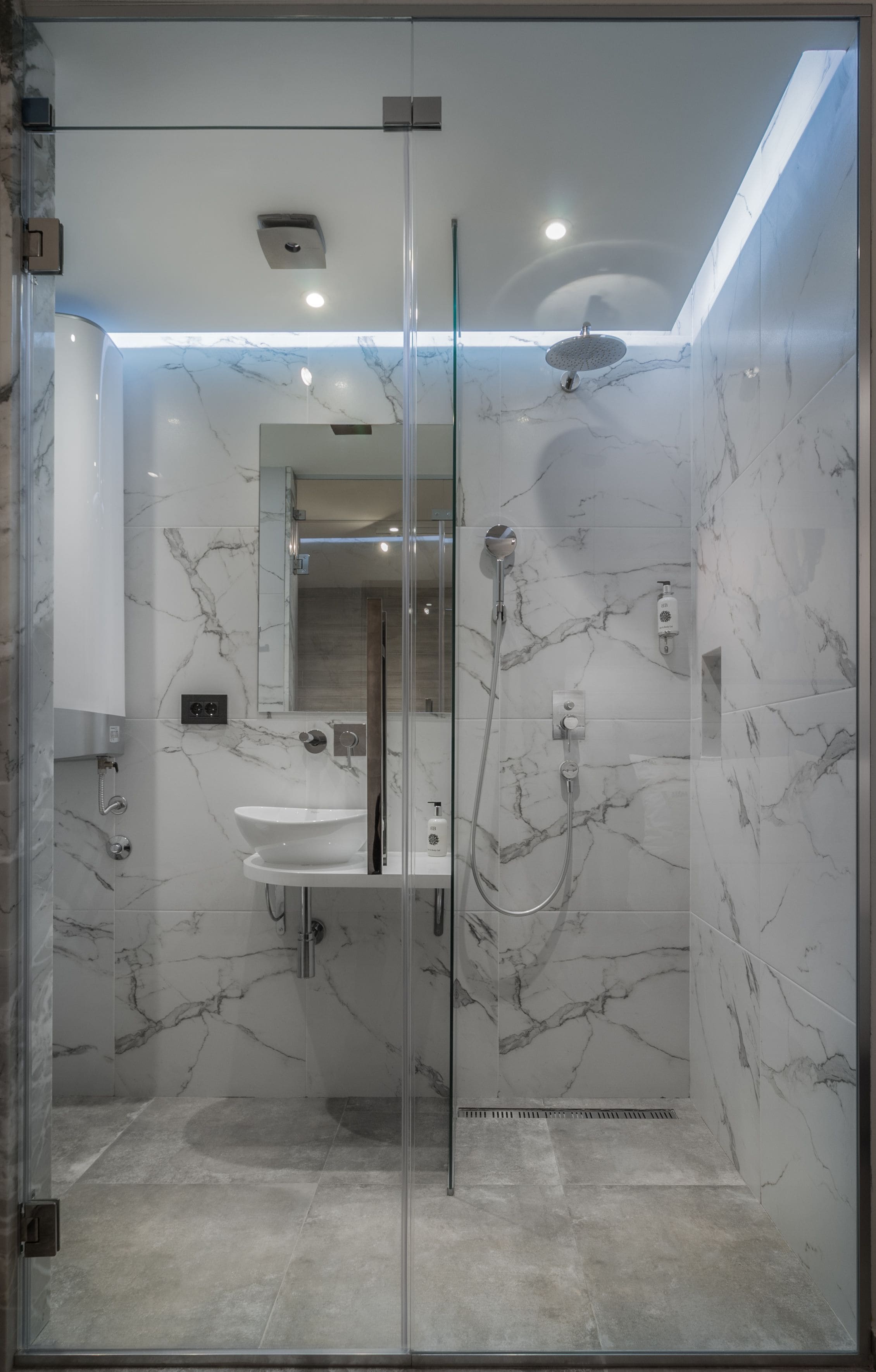 A modern bathroom with a glass-enclosed shower, marble walls, and a built-in sink.