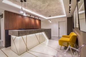 A reception area with a modern reception desk, a yellow chair, and a glass table.