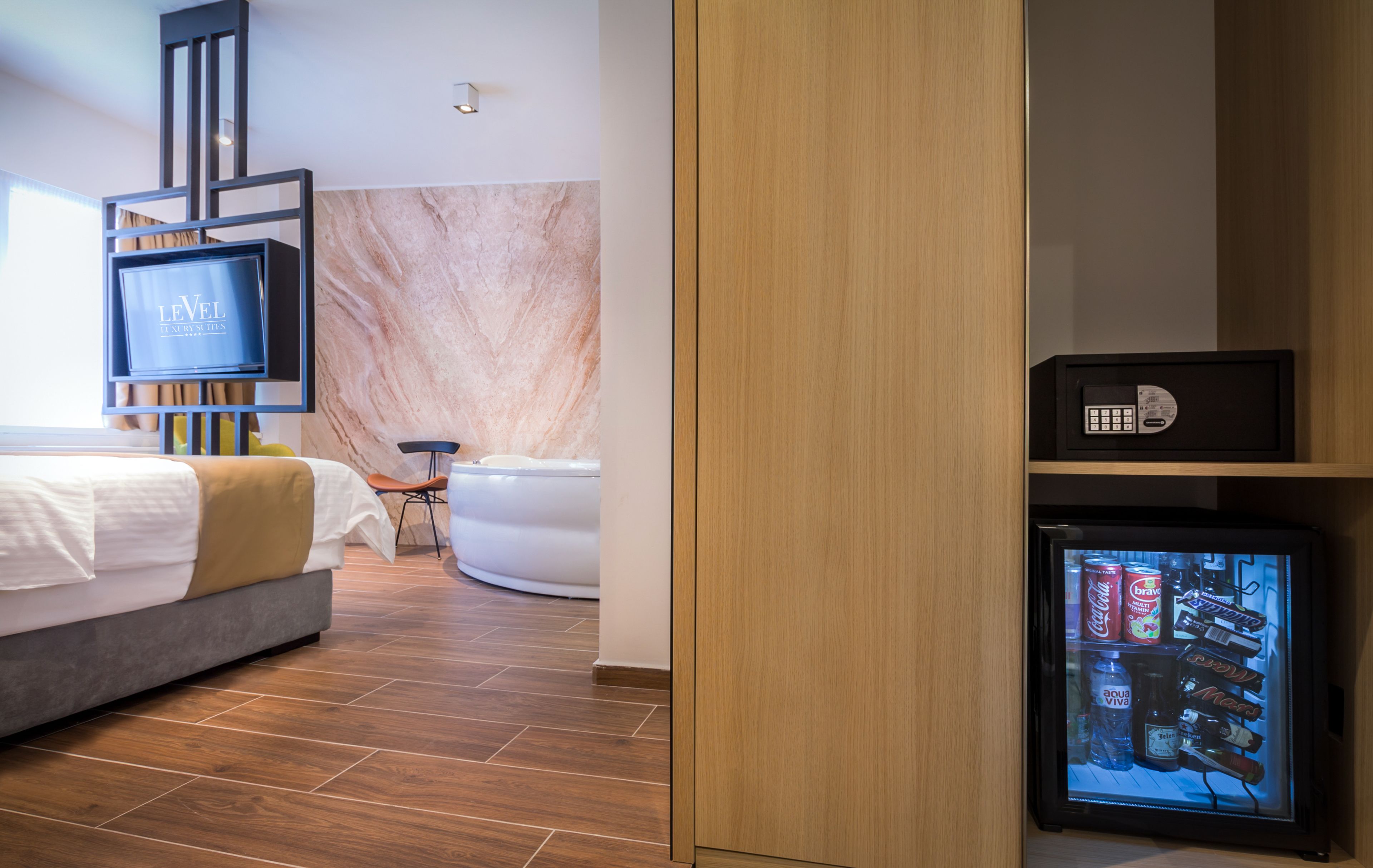 Una habitación de hotel moderna con cama, televisor, minibar y baño con bañera.