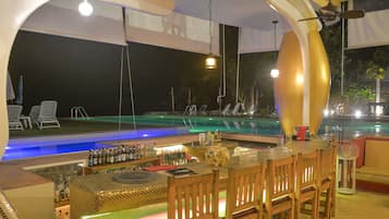 A bar area with a pool view, bar stools, and a pool table.
