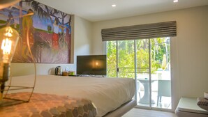 Un dormitorio con cama, televisión, ventana con vistas a zonas verdes y un cuadro en la pared.