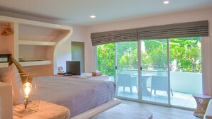 Un dormitorio con una cama grande, televisión, mesita de noche y vistas a un balcón con mobiliario exterior.
