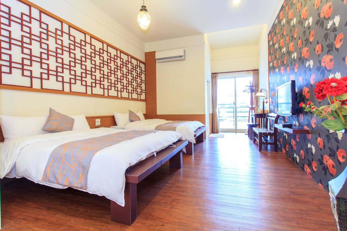 Quarto de hotel com uma cama grande, um banco, uma televisão e um painel decorativo.