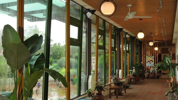 A spacious indoor area with large windows, ceiling fans, and various plants. - Lotus Hostel Beicheng Zhuang (Luodong)
