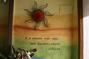 A wall with a decorative sun and a Spanish quote.